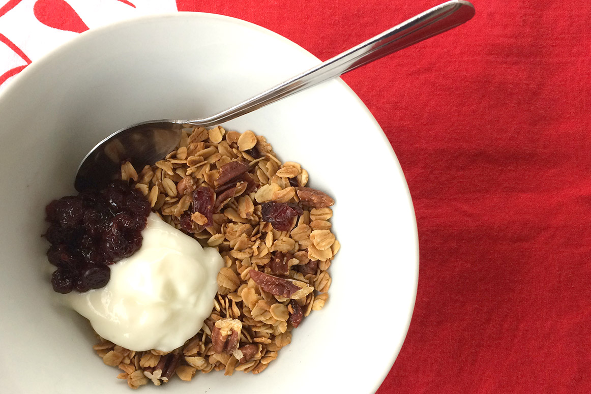 Granola, yogurt and jam in a white bowl on a red background