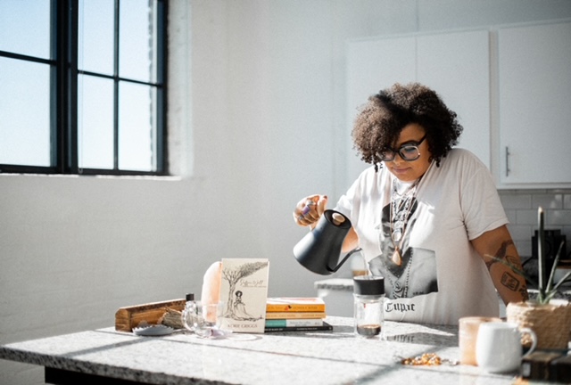Korie Griggs in a brightly lit kitchen pouring water from a kettle into a cup
