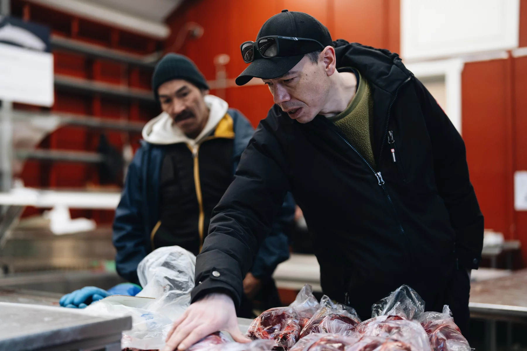 two men examining fish at a market