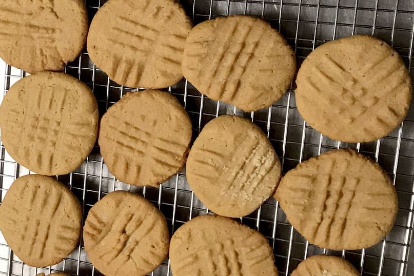 Peanutbutter cookies, with fork marks, on a cooling rack.