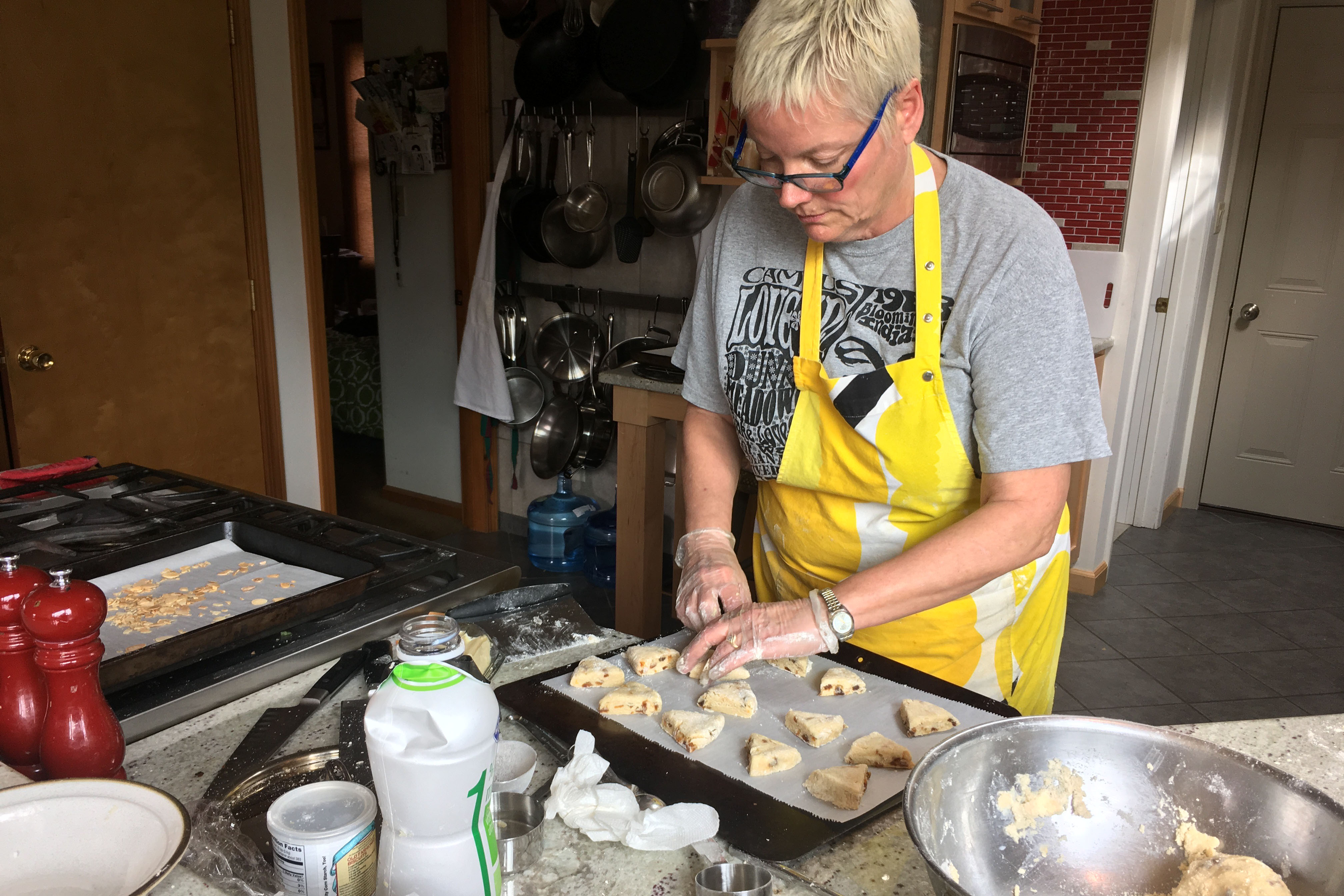 Marie Shakespeare standing in her kitchen placing unbaked scones on a baking sheet.