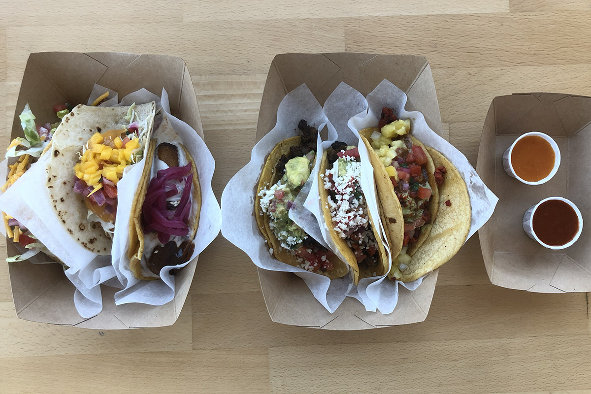 overhead view of two paper serving boats with 3 colorful tacos in each boat