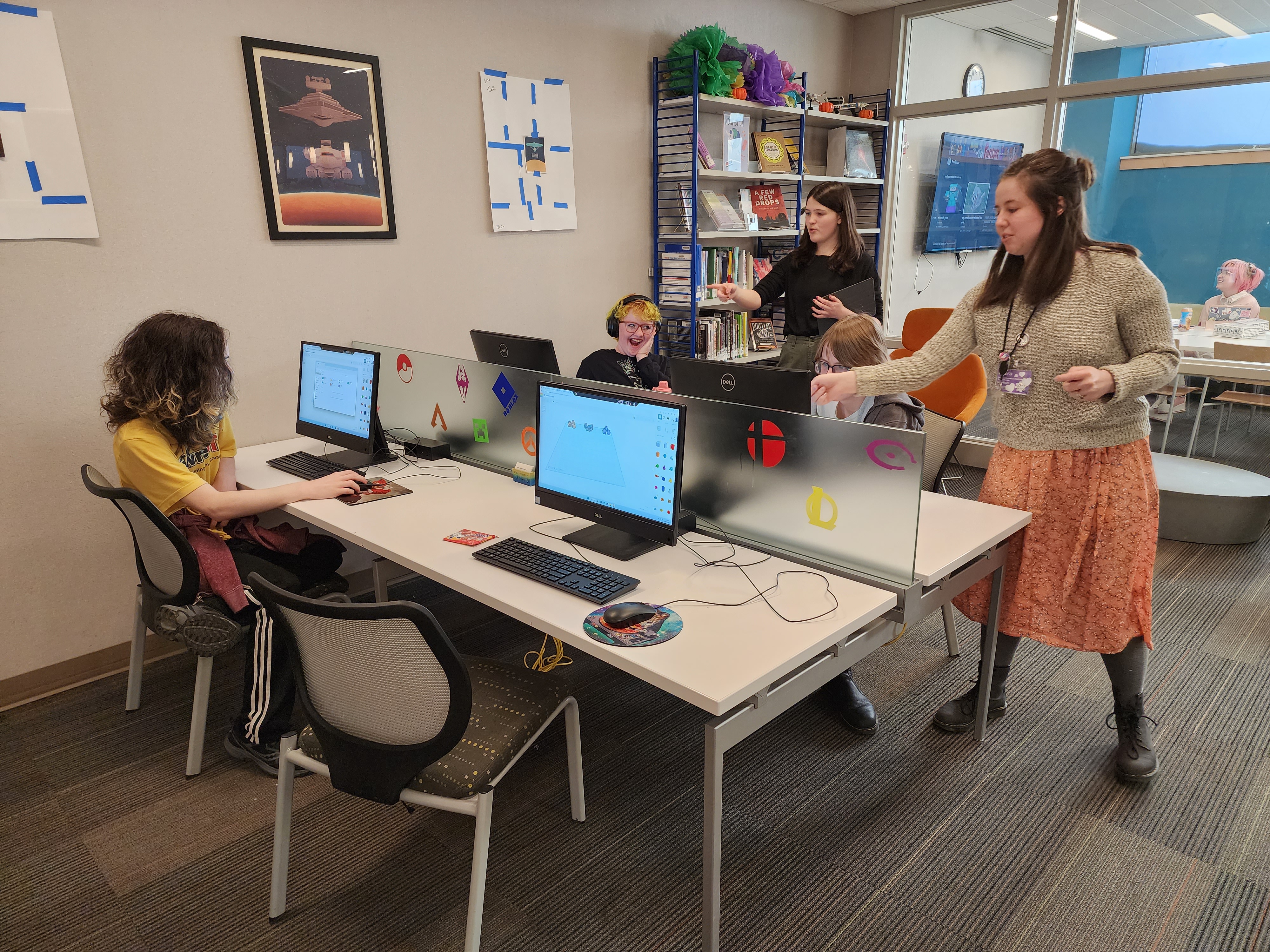 Teens at computers and employees standing at the MCPL teen space