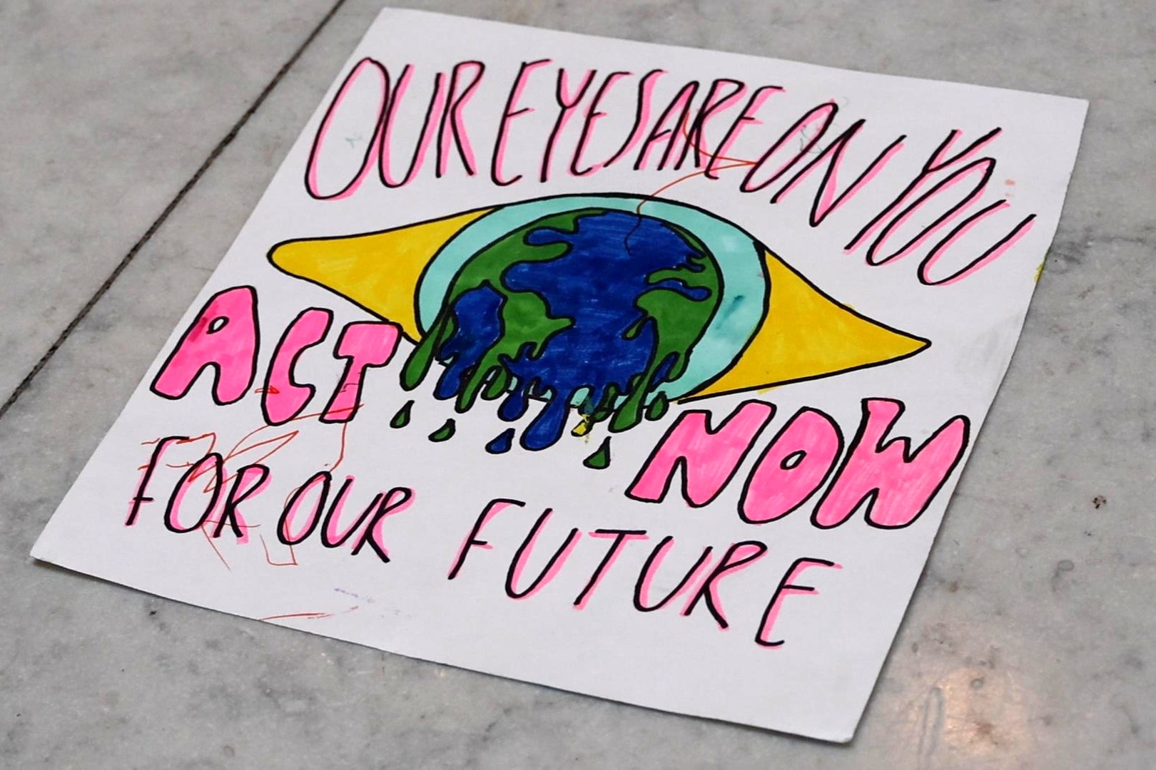 A poster at the Confront the Climate Crisis event March 17, 2025 at the statehouse reads "Our eyes are on you act now for our future"
