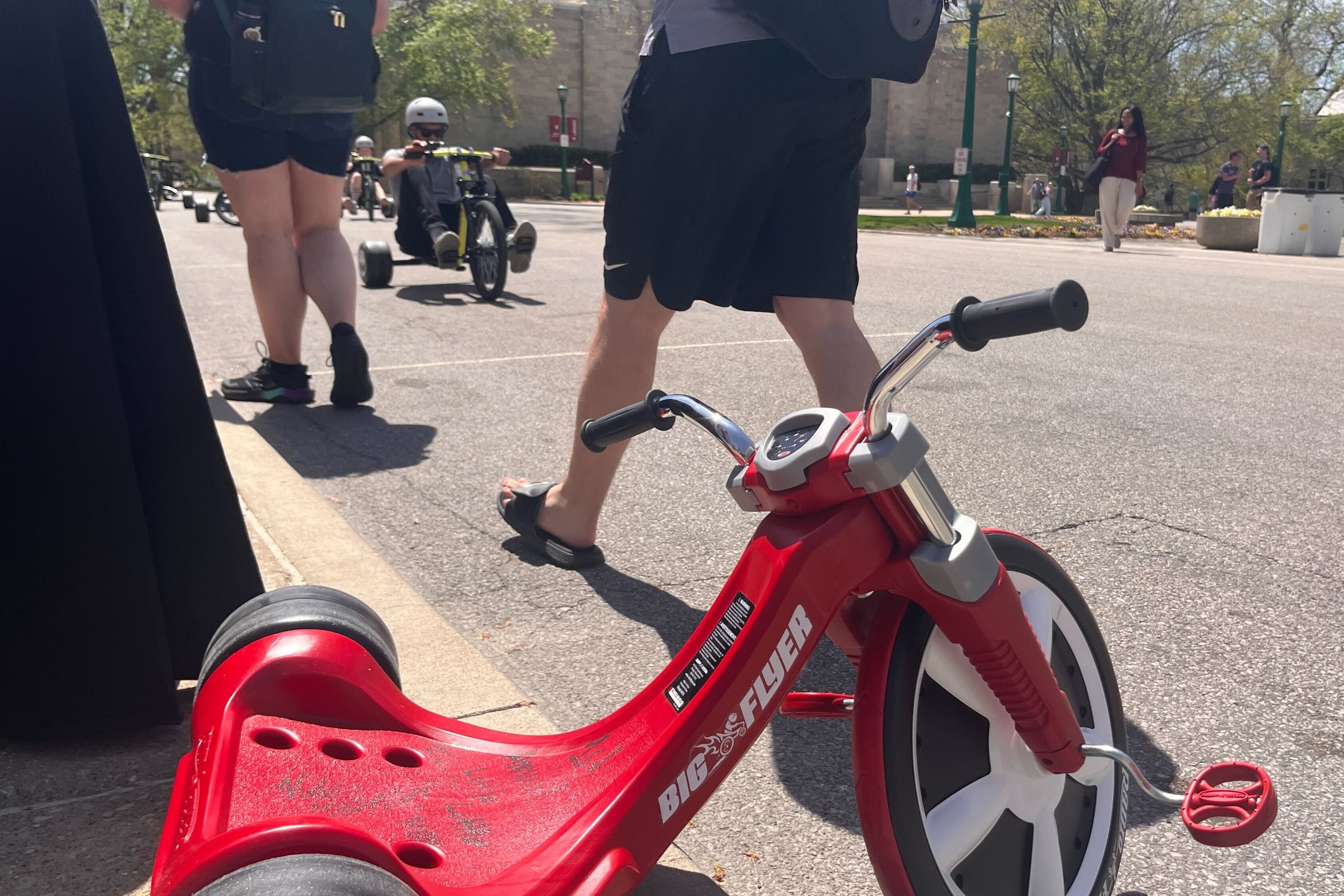 The tricyclists gear up for the race April 23, 2025. In the foreground rests the signed winner's trike from last year's race. 