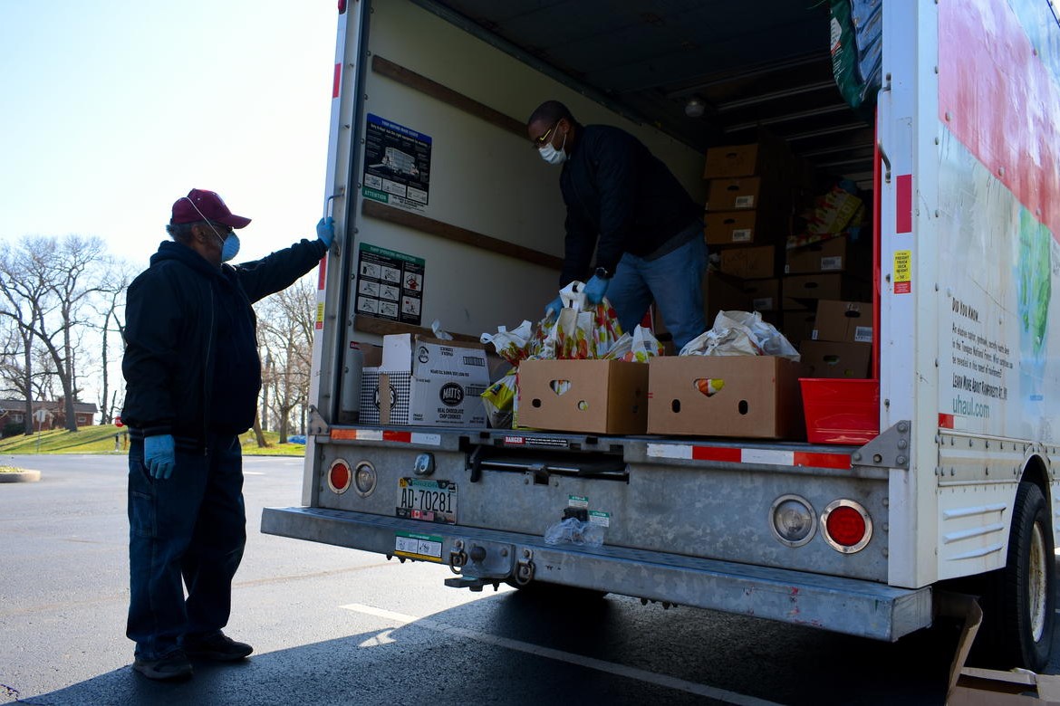 Church volunteers distribute free food out from a U-Haul truck in a parking lot. 