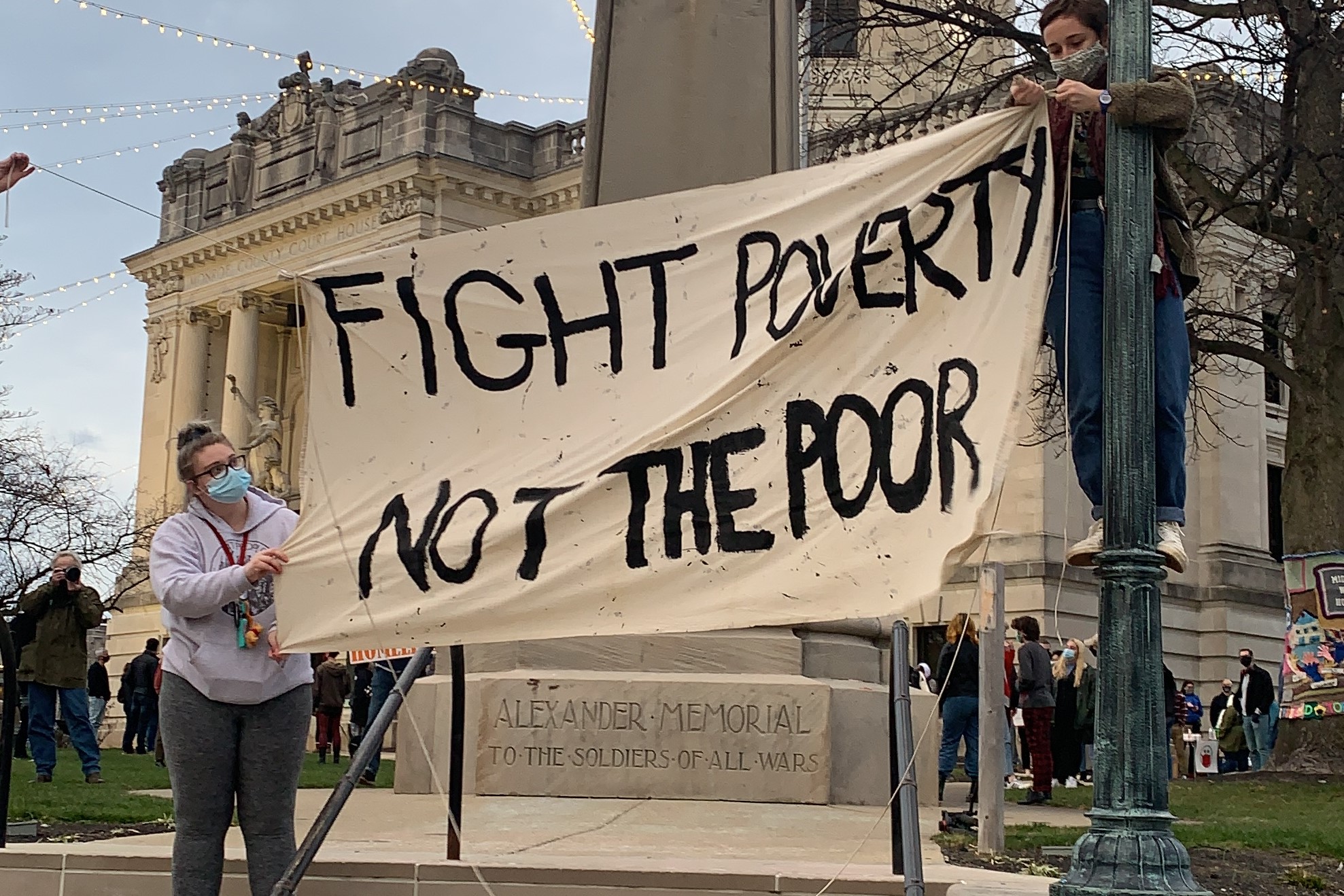 A photo of a sign that says "Fight Poverty, Not The Poor."