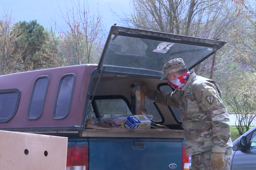 A photo of a National Guard soldier loading food into a car.