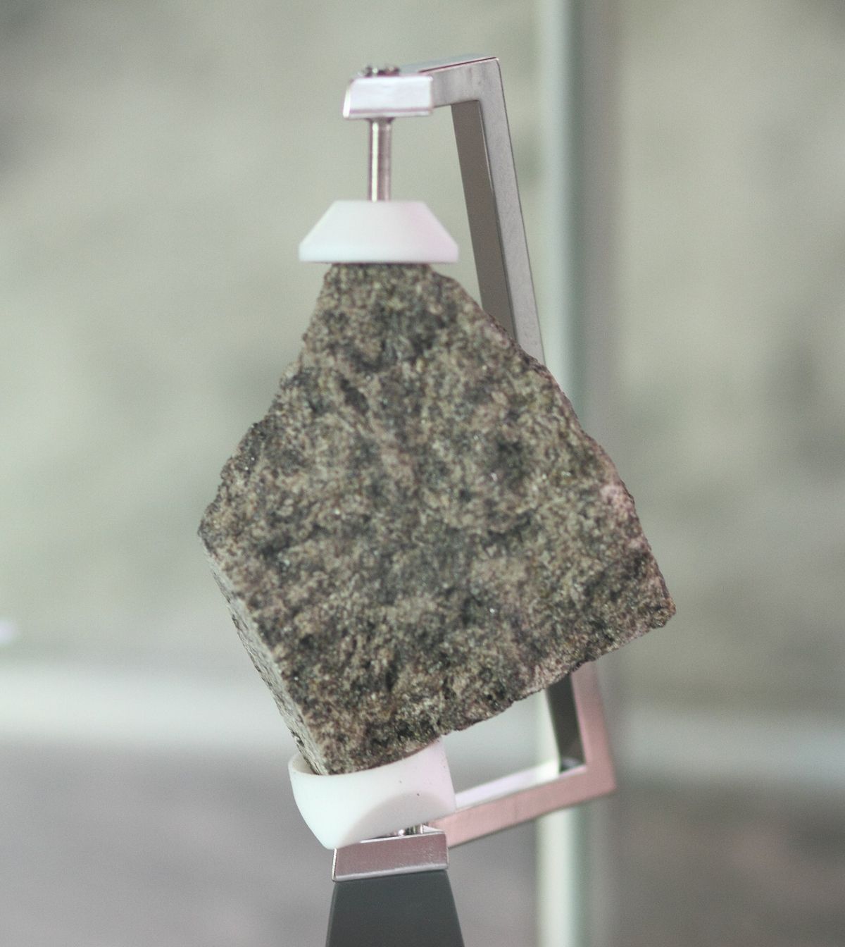 A sample of a moon rock suspended in a clamp's grip