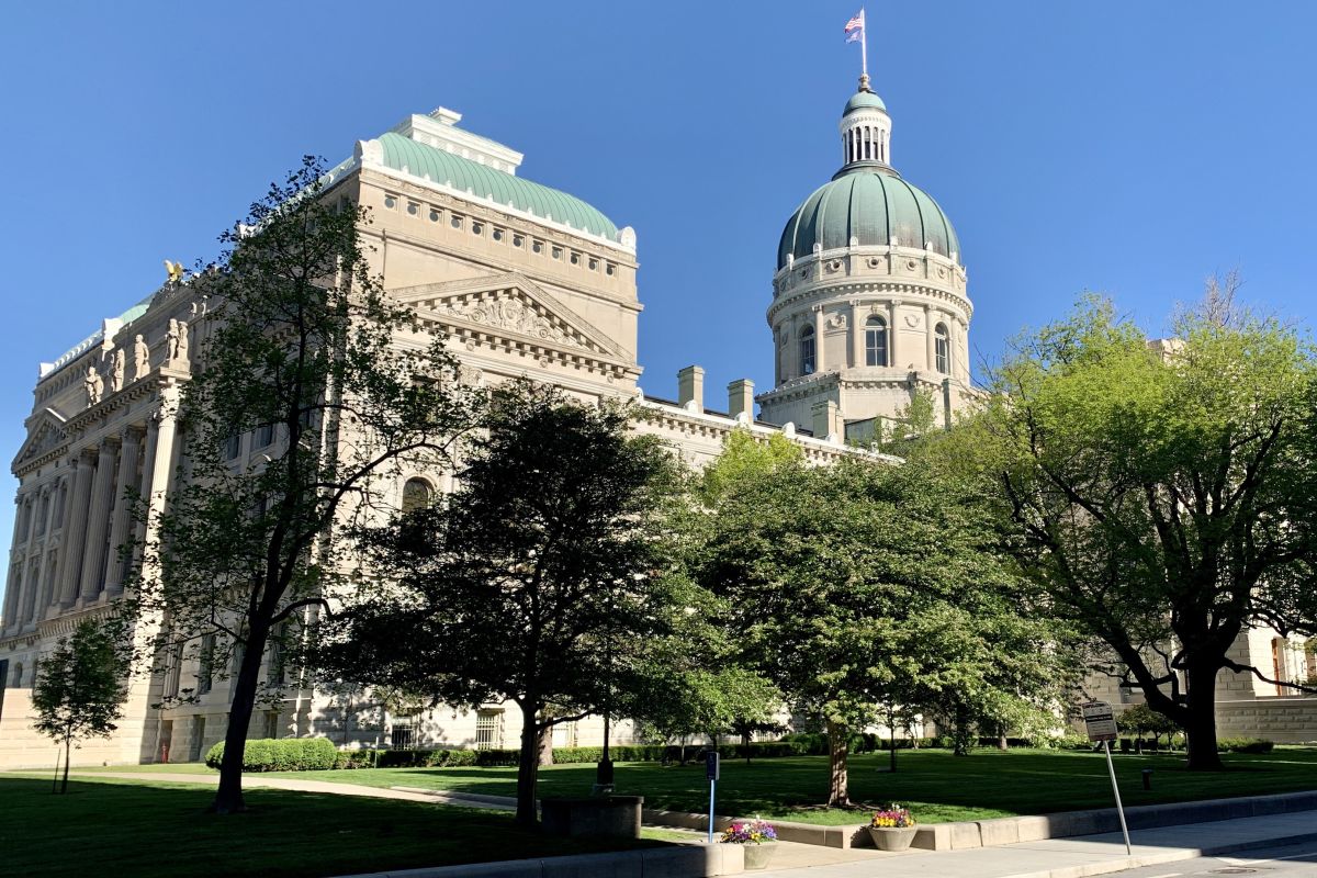 The southeastern exterior of the Indiana Statehouse, with trees in front of it.