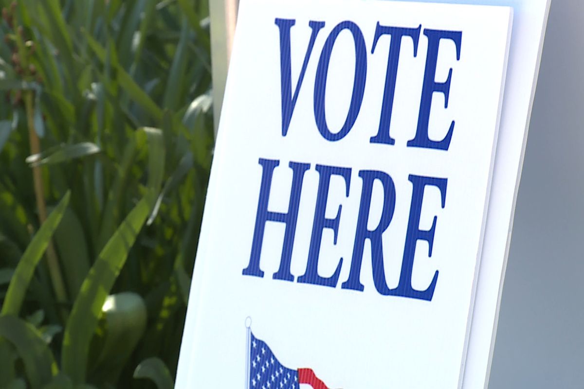 A white election sign that says vote here