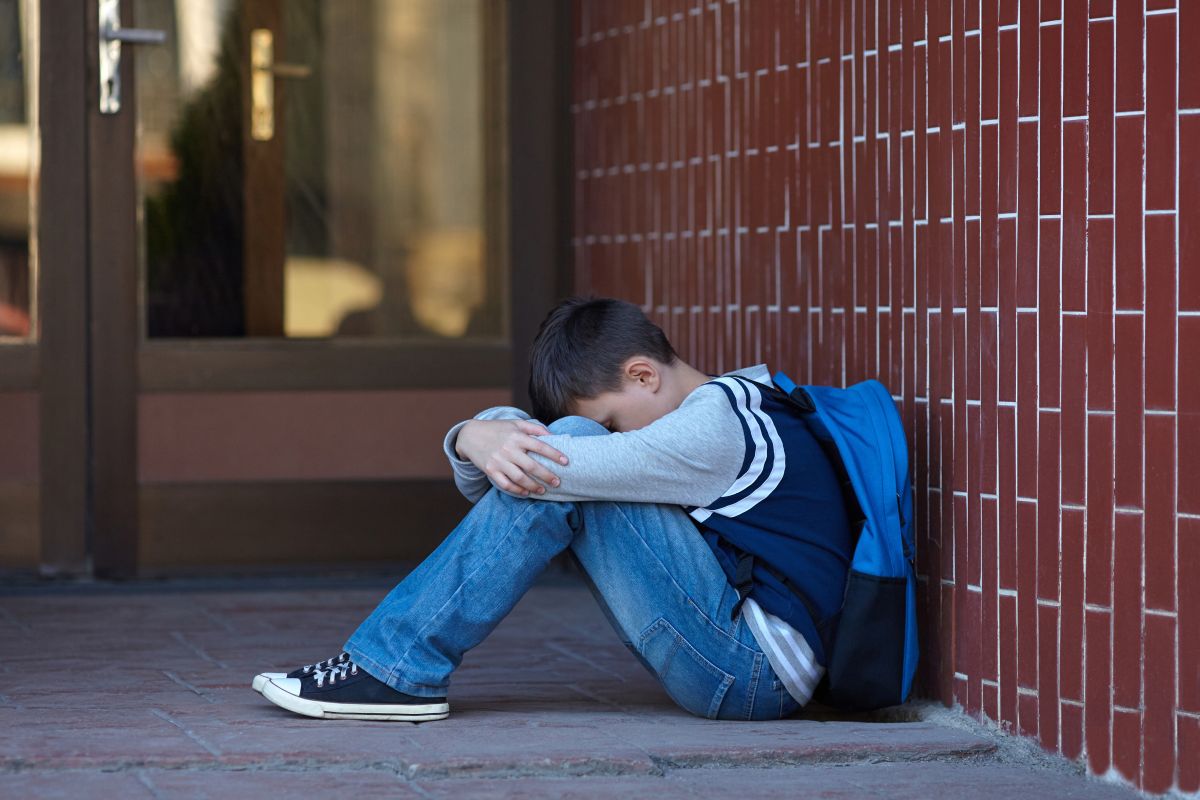 Schoolboy crying outside school stock photo