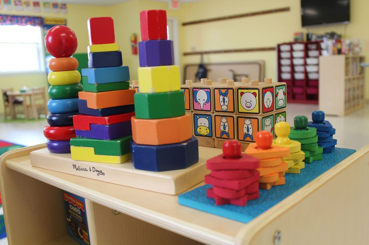 Bright rainbow colored blocks neatly stacked on top of a wooden shelf.