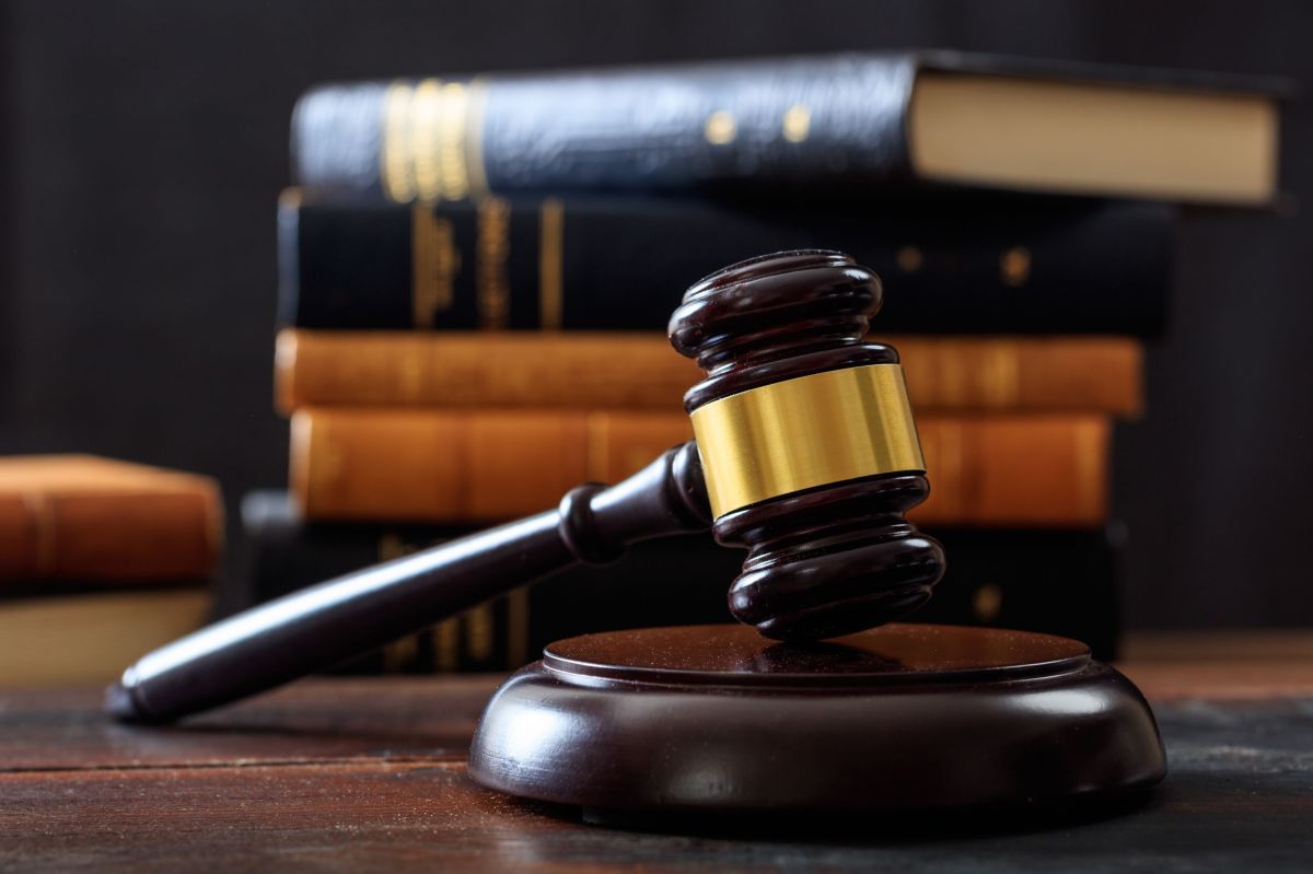 Judge gavel on a wooden desk, law books background