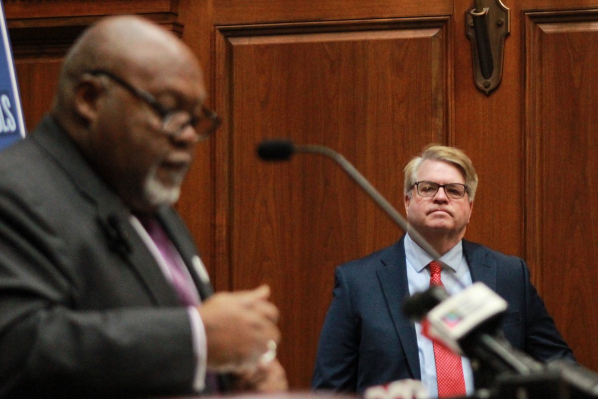 Greg Porter is a Black man, bald with a white goatee. He is wearing glasses and a black suit. Phil GiaQuinta is a White man with light-colored hair. He is wearing glasses and a blue suit.
