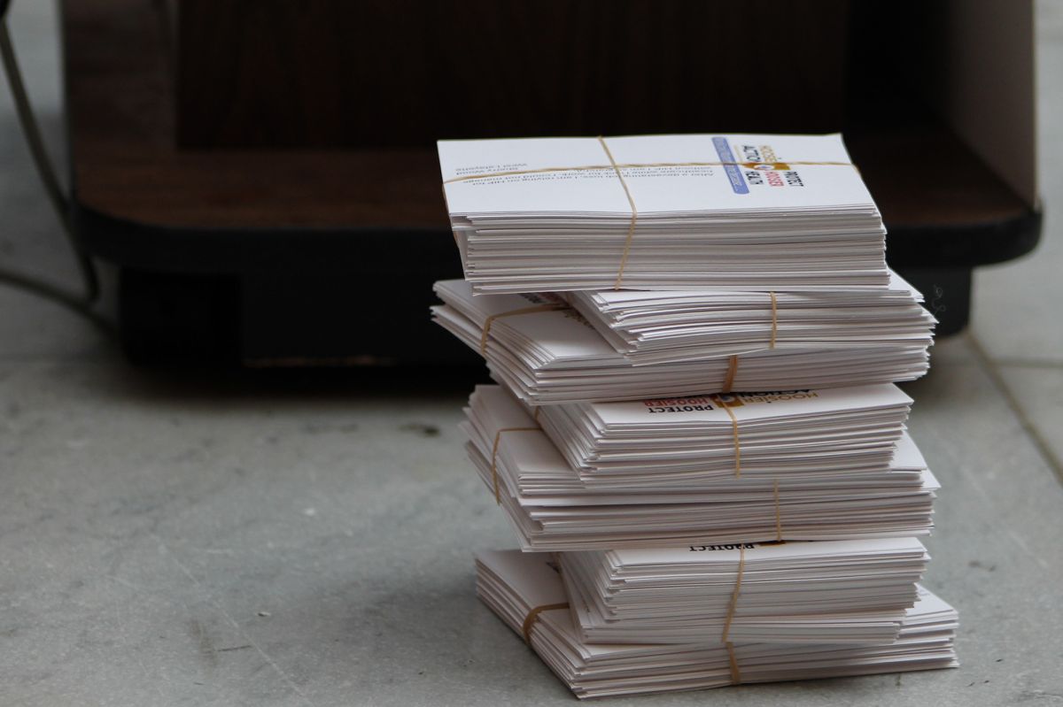 Index cards filled with cramped handwriting are held together with rubber bands. A pile is neatly stacked in front of a podium on the floor. They include the printed Hoosier Action logo and a large blank place for those at the rally to add t