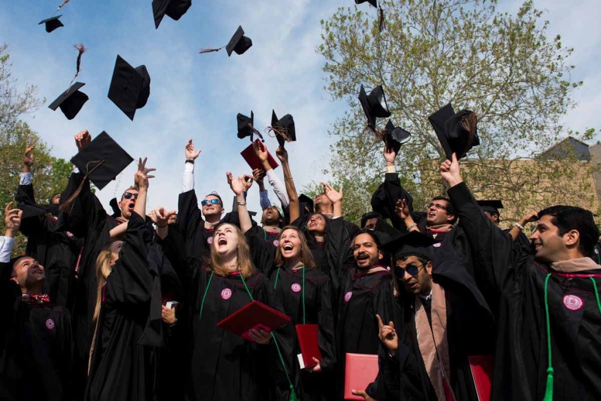 iu students throwing graduation black caps in the hair