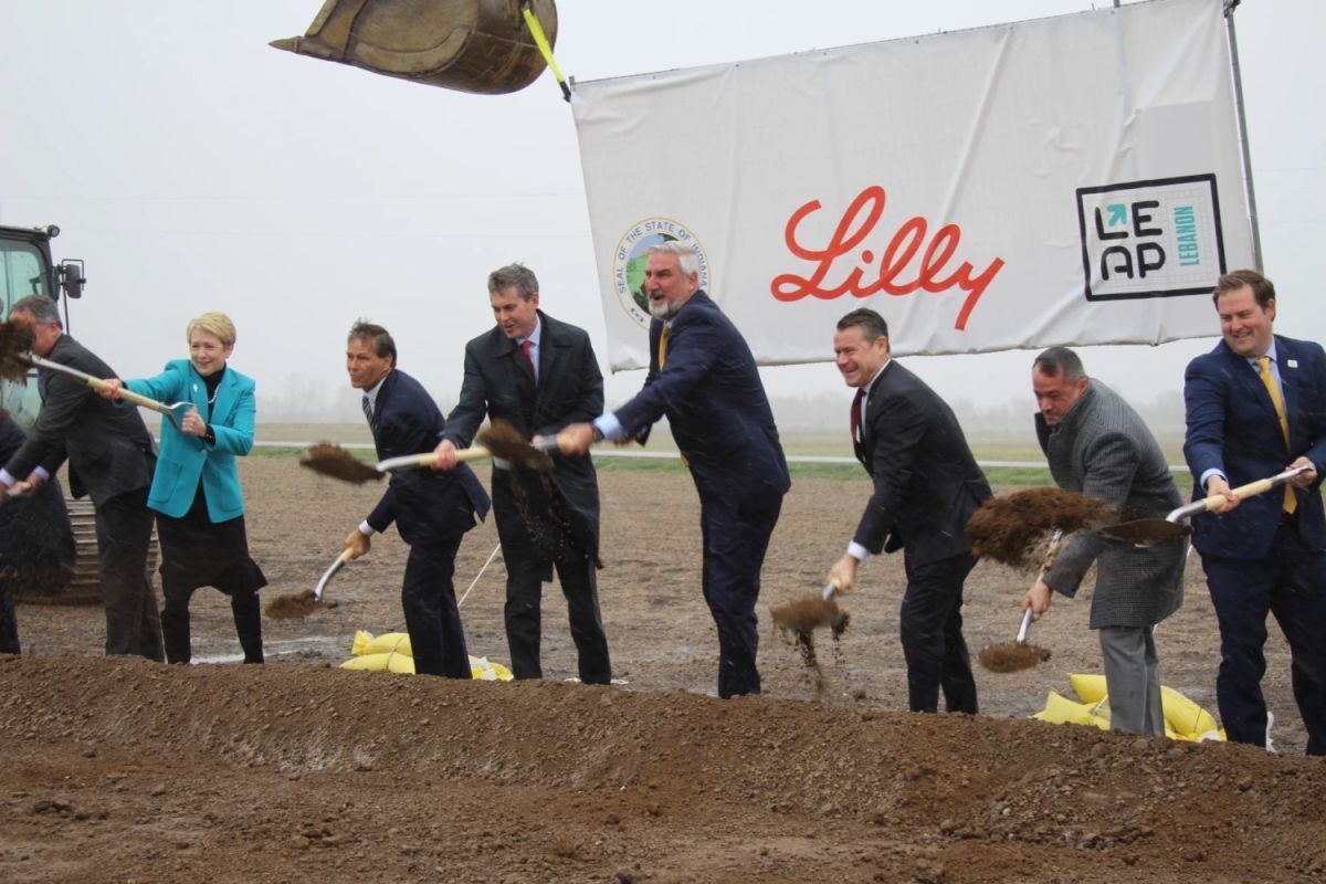 Former Gov. Eric Holcomb and other officials in suits and pantsuits move soil with shovels at the groundbreaking event for the Eli Lilly facility at the LEAP district in Boone County, 2023.