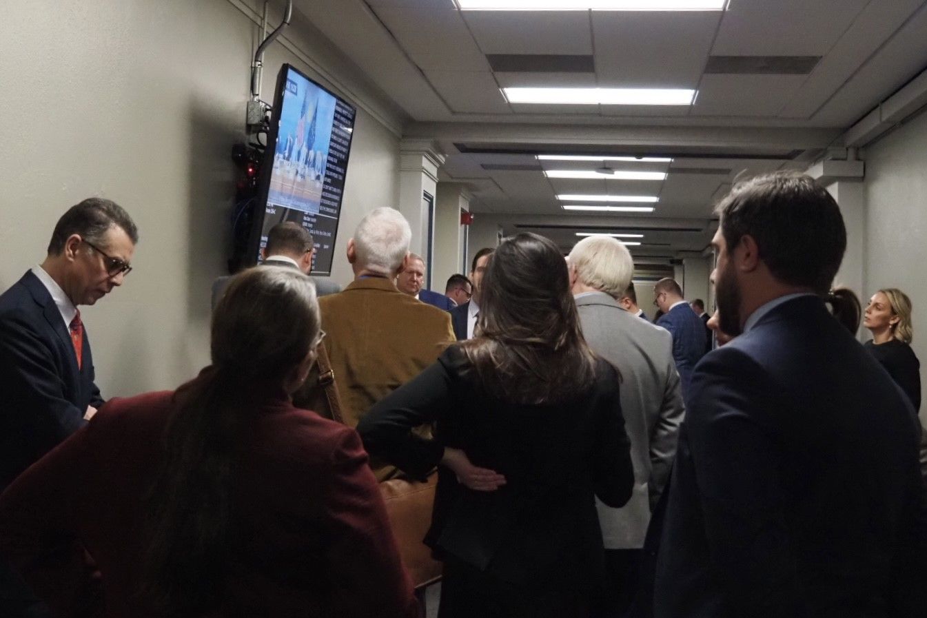 Lobbyists and other stakeholders gather around a screen to watch live committee proceedings on Tuesday, Feb. 4, 2025.