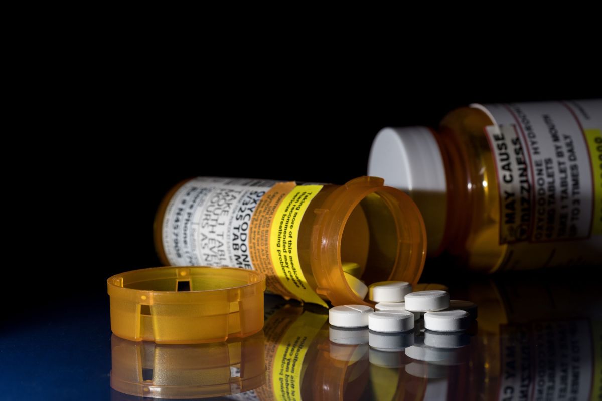 Prescription bottle for Oxycodone tablets and pills on glass table