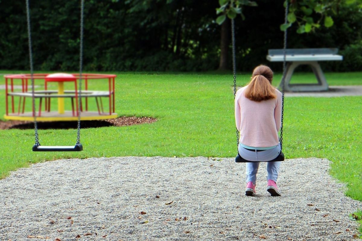 the back of a person on a swing in a playground