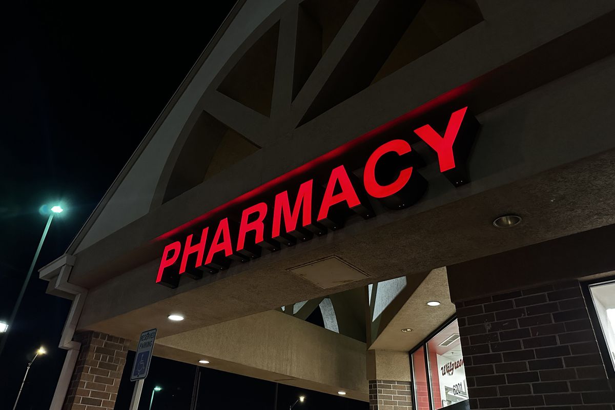 A red sign that reads "pharmacy" on the side of a Walgreens lit up at night. 