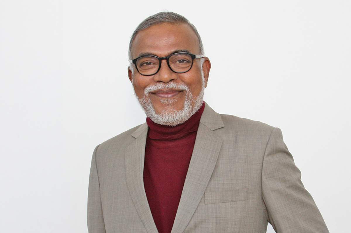 Narendra Jadhav in black hornrimmed glasses, maroon turtleneck sweater, and beige sport jacket.