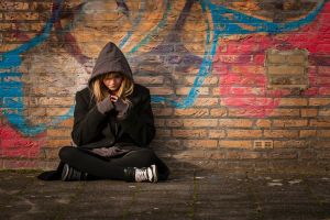 runaway girl sits in front of a wall with graffiti