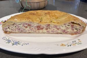 a pie cut in half, exposing the filling--diced meats and cheeses and egg