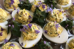 close up of deviled eggs with some small purple flowers scattered on top