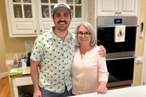 Mark Chilla stands next to his mom, Gay Chilla in a kitchen with white cabinets