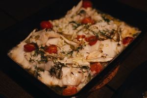 a halibut dish with tomatoes and herbs served in a pan