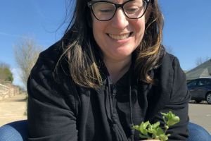 Stephanie Solomon's face smiling holding a plant spring