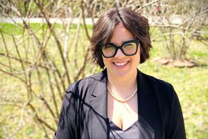 Erin Aquino, in a professional outfit, smiling, outdoors