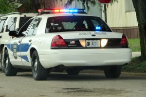 A neon sign reading &amp;amp;amp;quot;Police&amp;amp;amp;quot; hangs in a window. A county courthouse is seen in the window&amp;amp;amp;apos;s reflection.